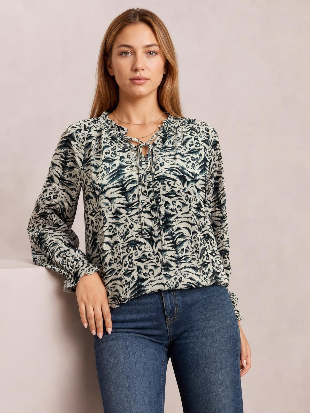Model wearing a printed tie-neck blouse with frill trim, long flounce sleeves, and a relaxed long silhouette in gray, black, and ivory tones.