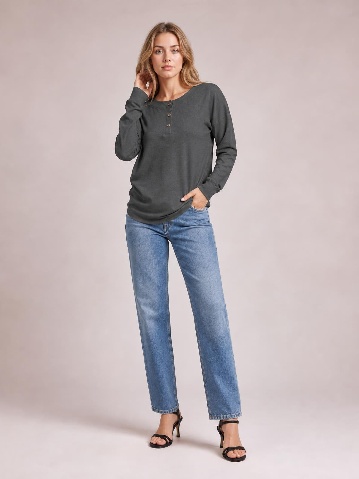Model poses in a charcoal quarter-button dropped-shoulder blouse with long sleeves, a relaxed silhouette, and a rounded neckline.
