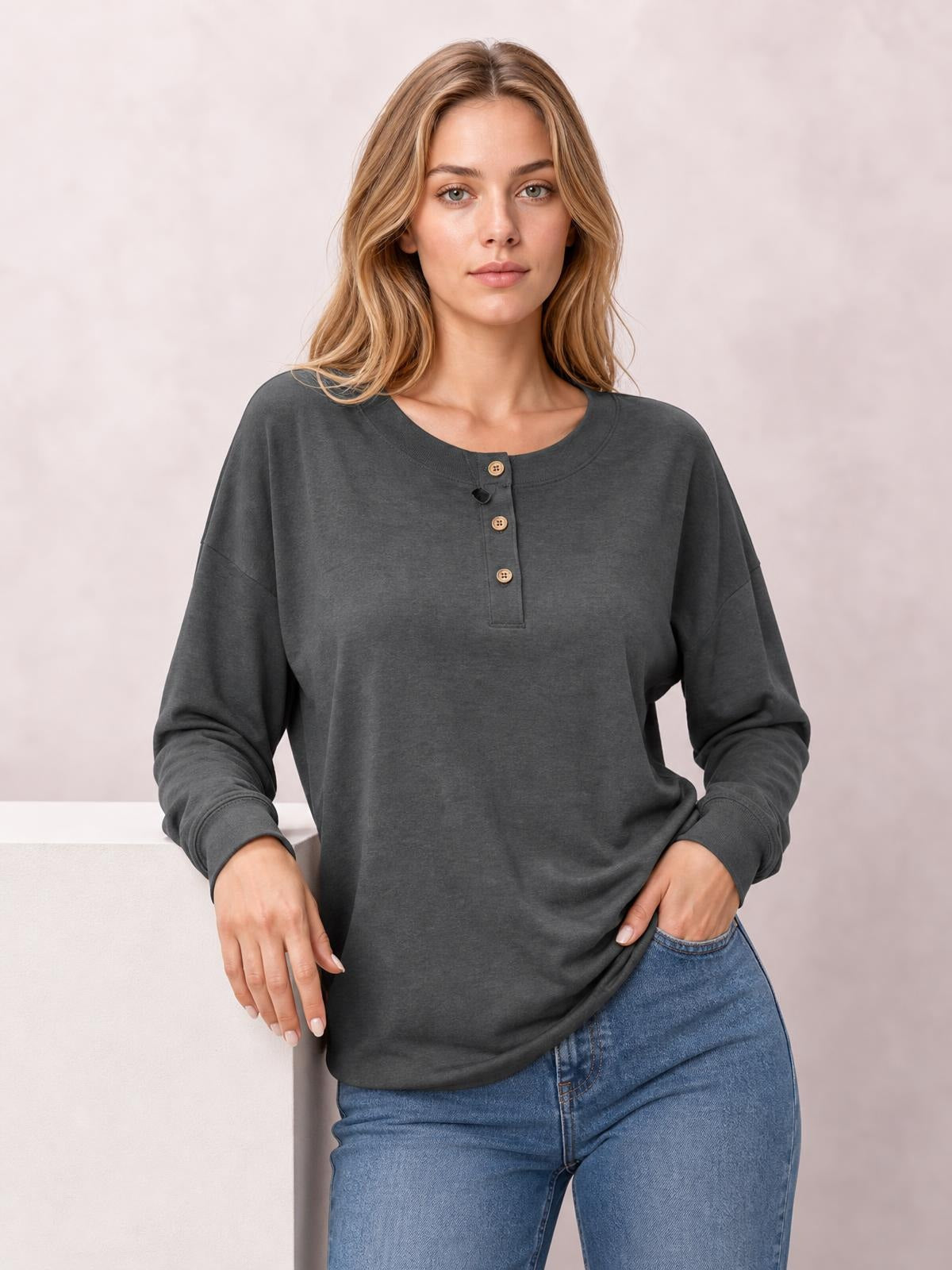 Model wears a charcoal quarter-button dropped-shoulder blouse with a relaxed silhouette, crew neckline, long sleeves, and ribbed cuffs.