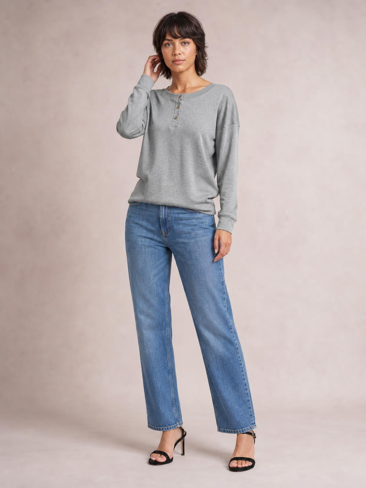 Model wearing a gray quarter-button dropped-shoulder blouse with a relaxed silhouette, long sleeves, ribbed cuffs, and a round neckline.