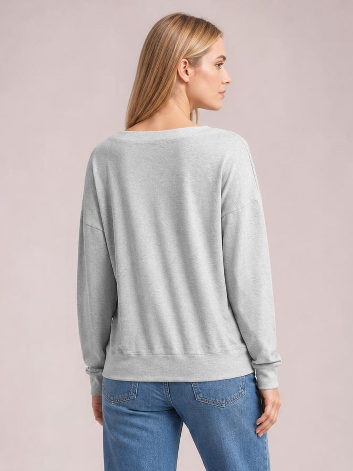 A model wears a light gray dropped-shoulder blouse with long sleeves, ribbed cuffs and hem, shown from the back in a relaxed standing pose.