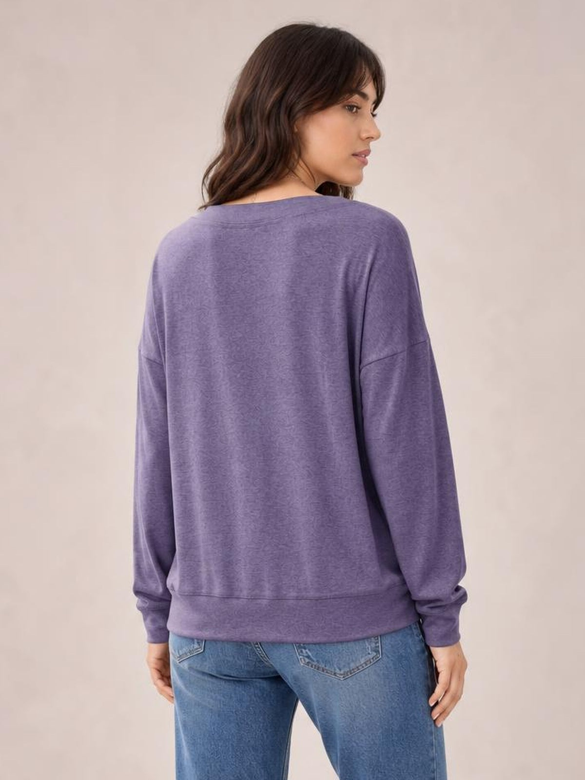 Model shown from behind wearing a lavender-purple dropped shoulder blouse with a relaxed silhouette, long sleeves, ribbed cuffs, and a ribbed hem.