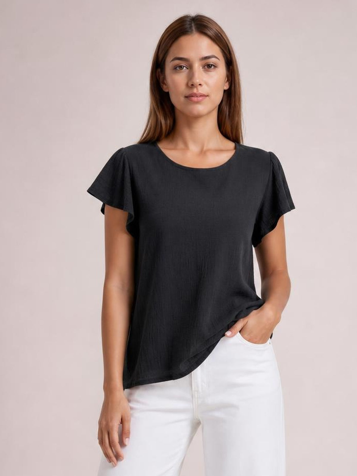 A model poses in a solid black round-neck top with short flutter sleeves and a relaxed regular silhouette, lifting the hem with one hand.