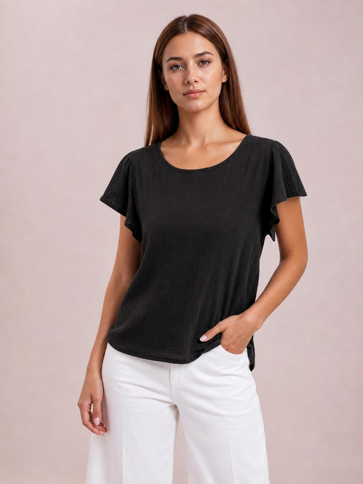 Model wears a solid black round-neck shirt with short flutter sleeves and a relaxed regular silhouette, posing with one hand in a pocket.