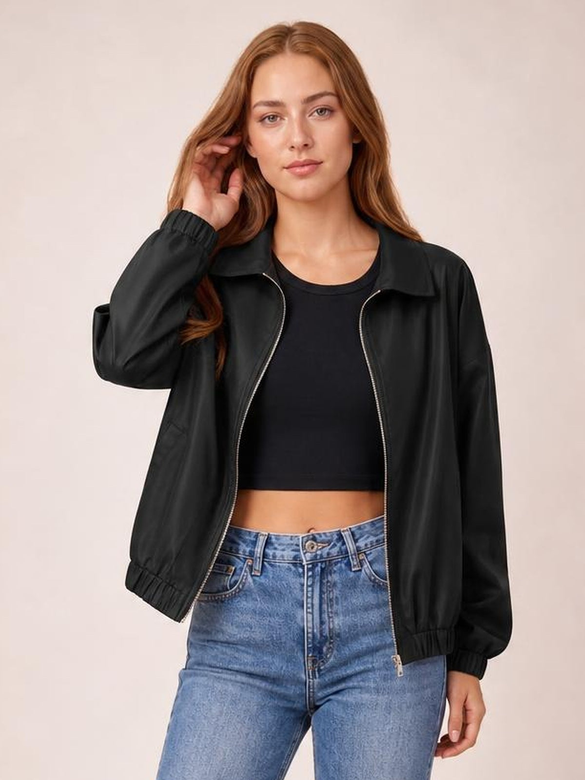 Model poses in a black zip-up dropped shoulder jacket with a relaxed silhouette, collared neckline, side pockets, and elastic cuffs over a cropped top.