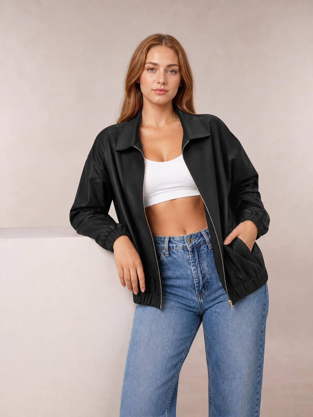 A model wears a black polyester zip-up jacket with dropped shoulders, a pointed collar, roomy sleeves, elastic cuffs and hem, and front pockets.