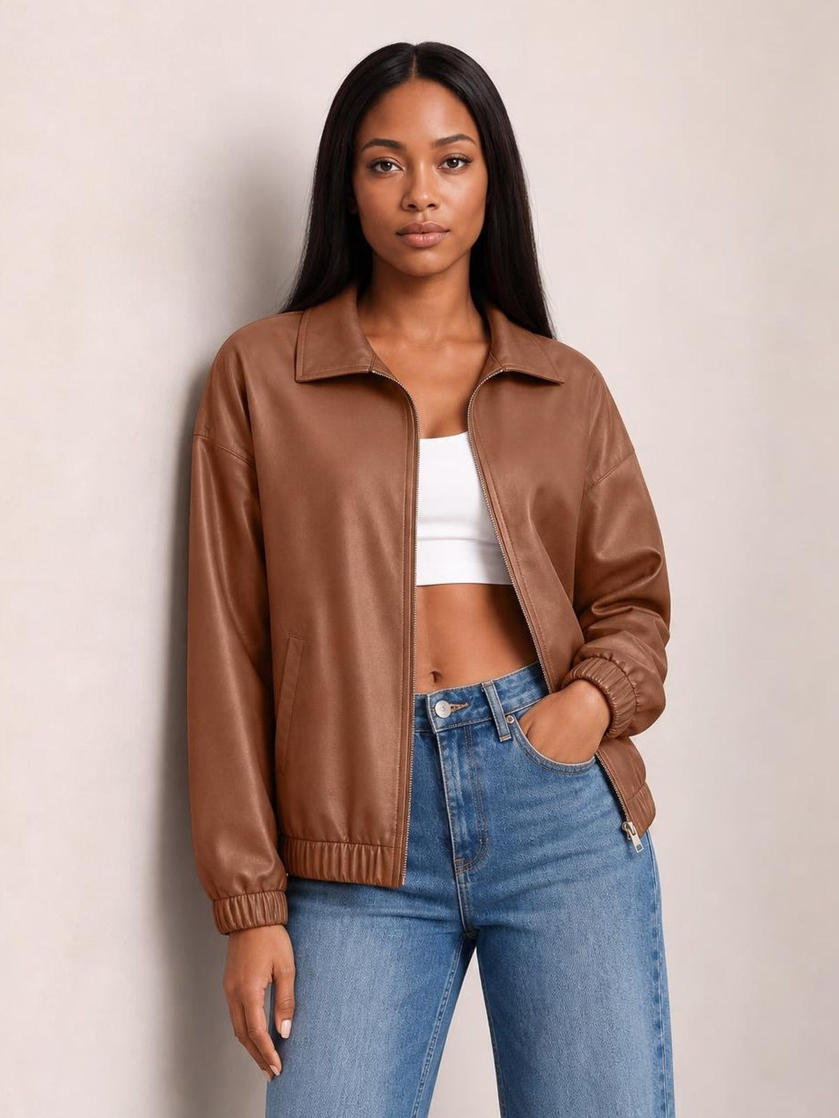 Model wearing a brown zip-up dropped shoulder jacket with a relaxed silhouette, pointed collar, front pockets, and elasticized cuffs and hem.