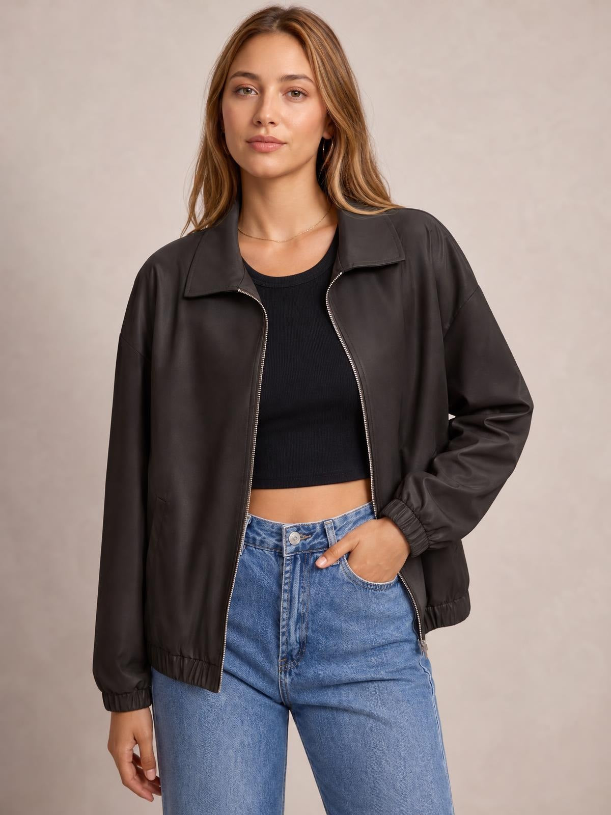 Model wearing a black zip-up dropped shoulder jacket with a relaxed silhouette, pointed collar, elastic cuffs and hem, and visible front pockets.