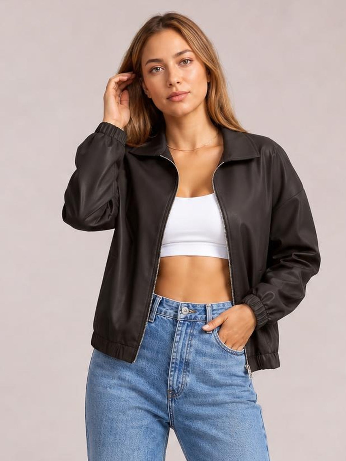A model poses in a black zip-up dropped-shoulder jacket with a relaxed silhouette, raised collar, ribbed cuffs and hem, and front pockets.
