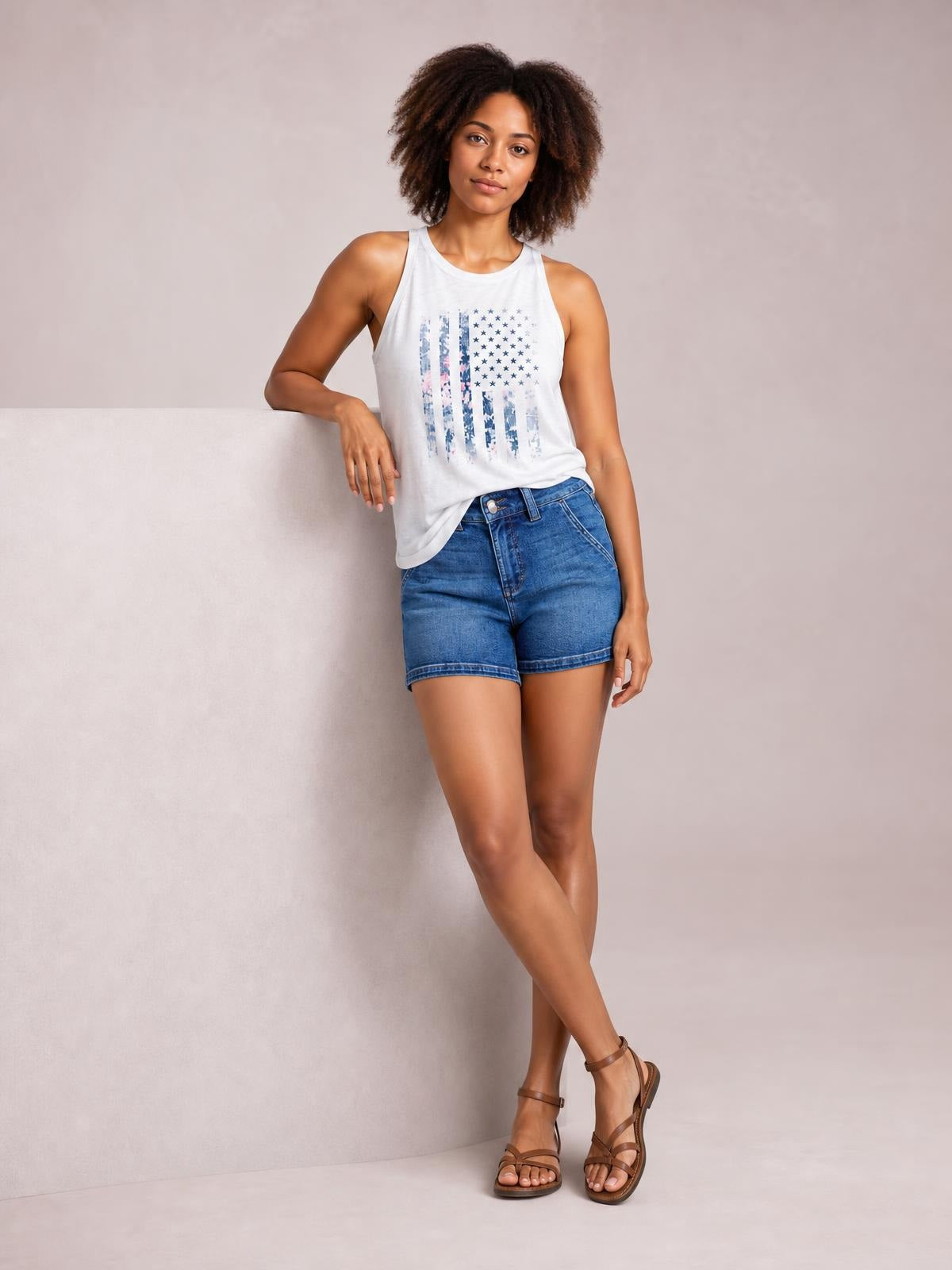 Model poses in blue high-waisted denim shorts with a double button waistband, zip fly, belt loops, and cuffed hems.