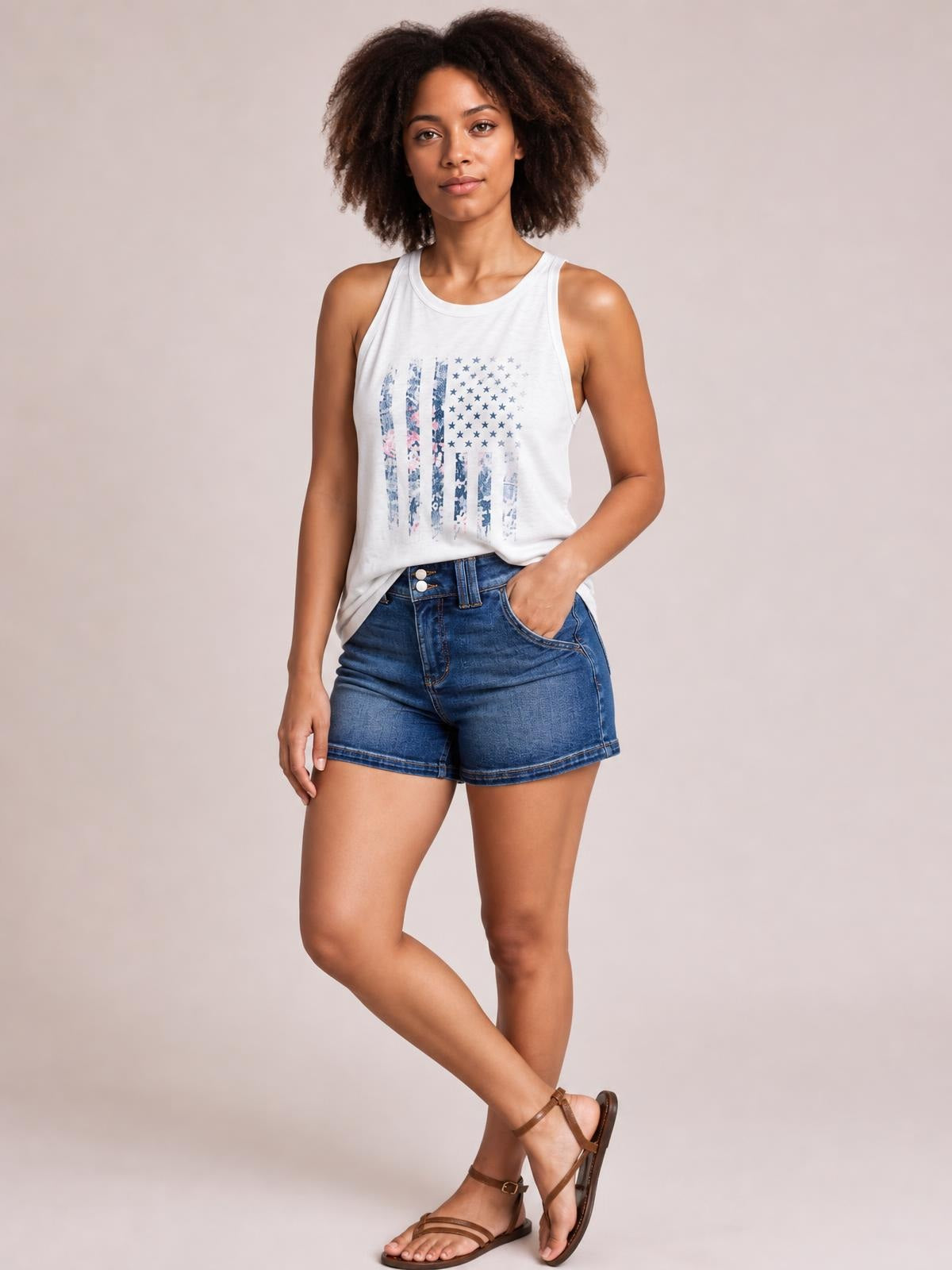 A model poses with one hand in the pocket, wearing medium-wash high-waisted denim shorts with a double-button waistband, front pockets, and a straight silhouette.