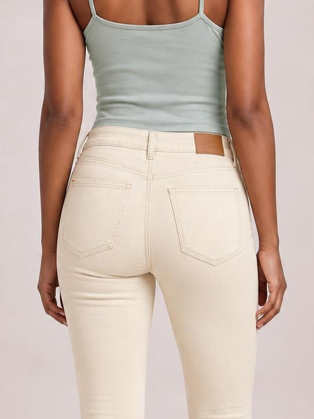 Back view of a model wearing cream JuBlue garment dyed tummy control skinny jeans with a high-rise waist, belt loops, and two back pockets.