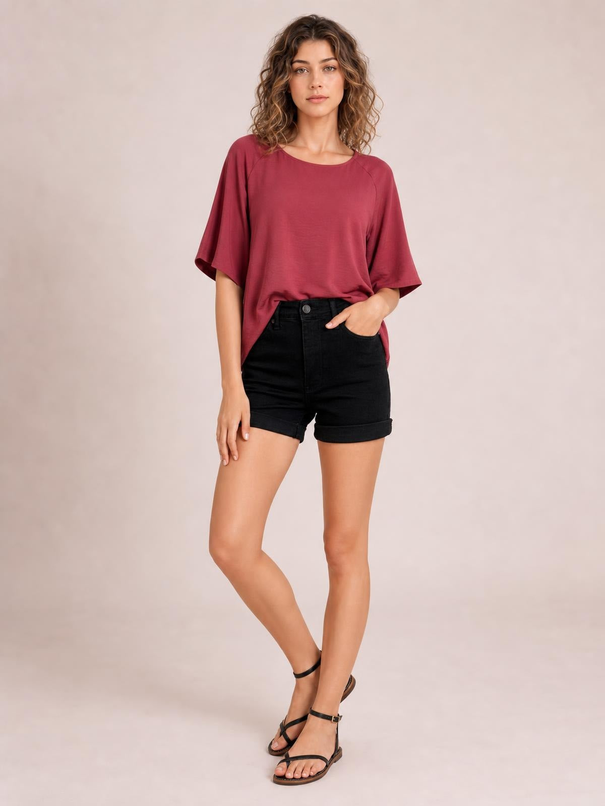 Model stands with one hand in the pocket wearing black high-waisted tummy-control denim shorts with a fitted silhouette, button fly, and cuffed hems.