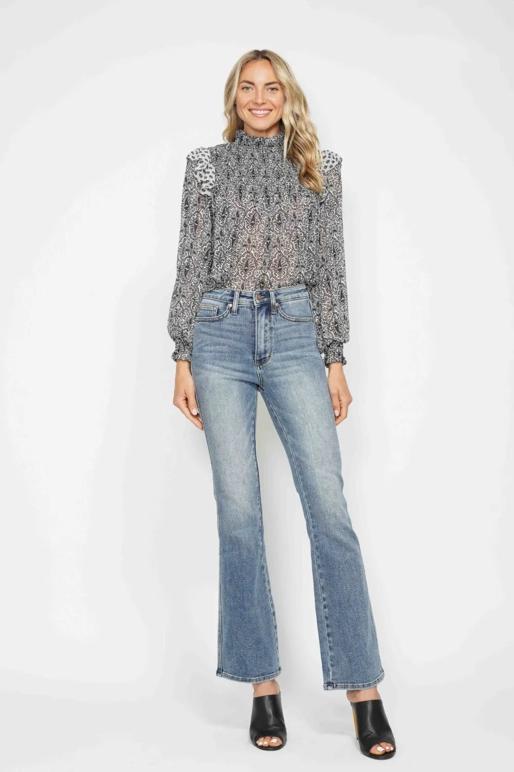Model stands in light-wash tummy control jeans with a high-rise waistband, front pockets, belt loops, button fly, and a relaxed bootcut silhouette.