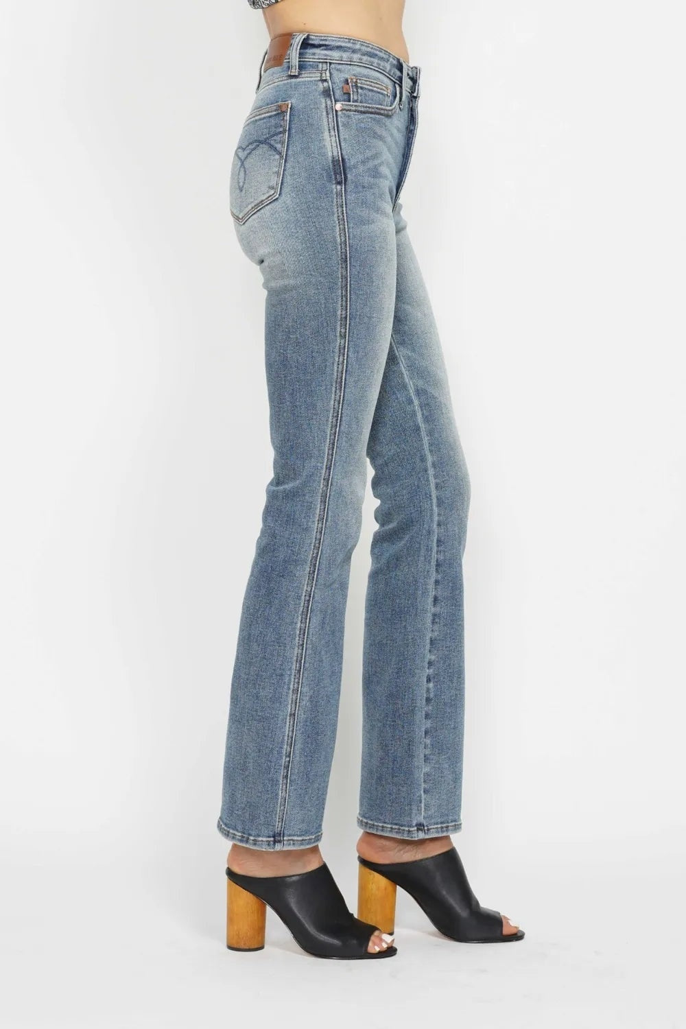 A model stands in profile wearing light-wash tummy control bootcut jeans with a high-rise waistband, belt loops, back embroidered pocket, and slight stretch.