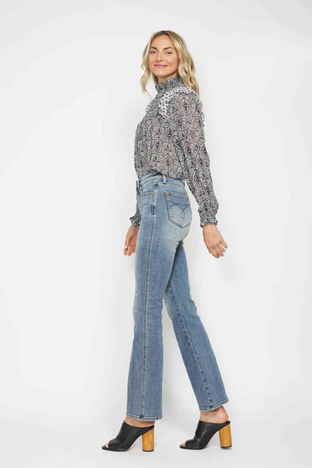 Model poses in light-wash tummy control jeans with embroidered back pockets and a flattering bootcut silhouette.