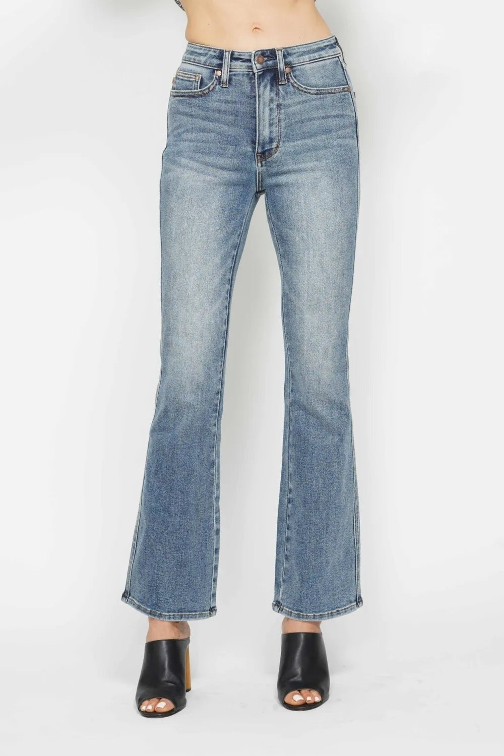Model stands in light-wash tummy control bootcut jeans with a high-rise waistband, five-pocket construction, front zip fly, and gently flared legs.