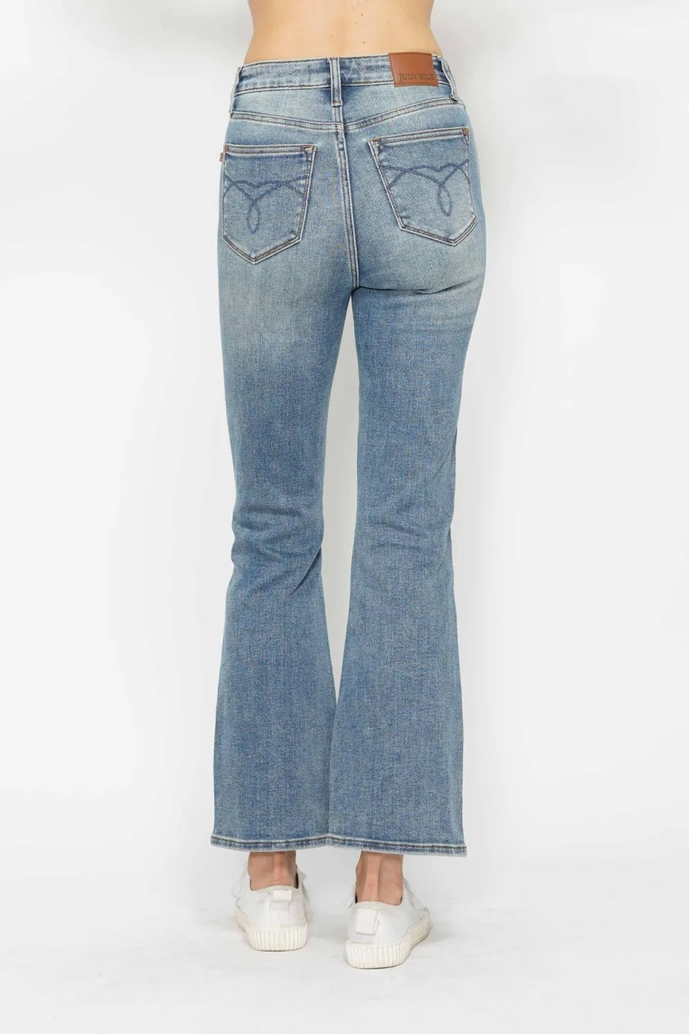 Model shown from the back wearing light-wash tummy control bootcut jeans with embroidered back pockets, belt loops, and a long flared silhouette.
