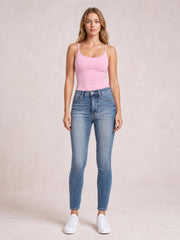Model standing front-facing in high-rise blue skinny jeans with a light contrast wash, tummy control waistband, classic pockets, and fitted ankle-length legs.
