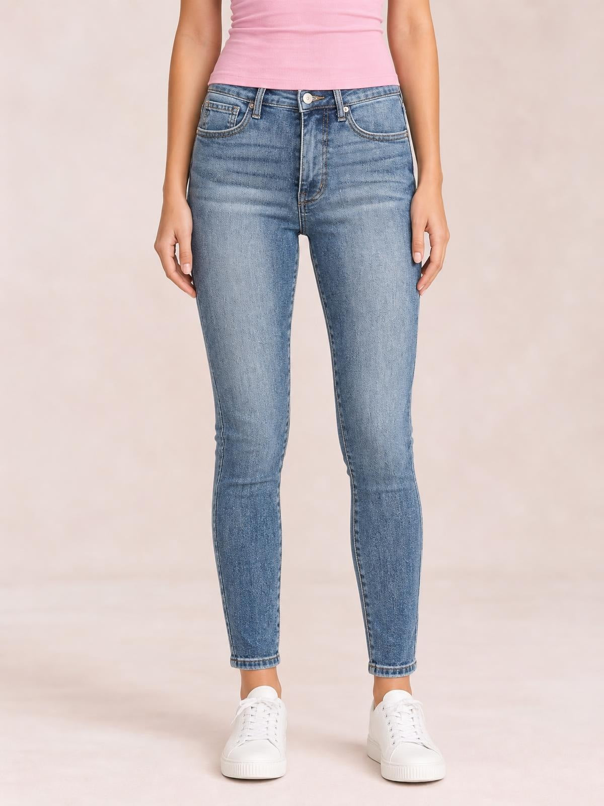 Model stands facing forward in high-rise blue contrast-wash skinny jeans with a tummy-control waist, belt loops, front pockets, and tapered legs.