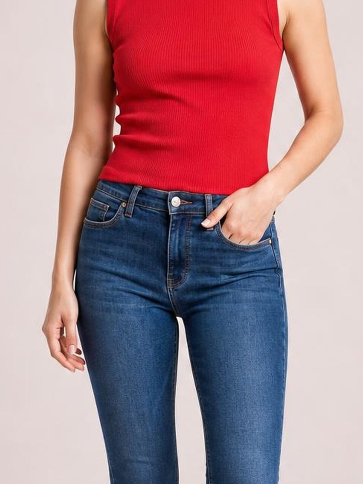 Model wearing dark blue washed thermal skinny jeans with a button fly and visible pockets, standing with one hand tucked into a pocket.