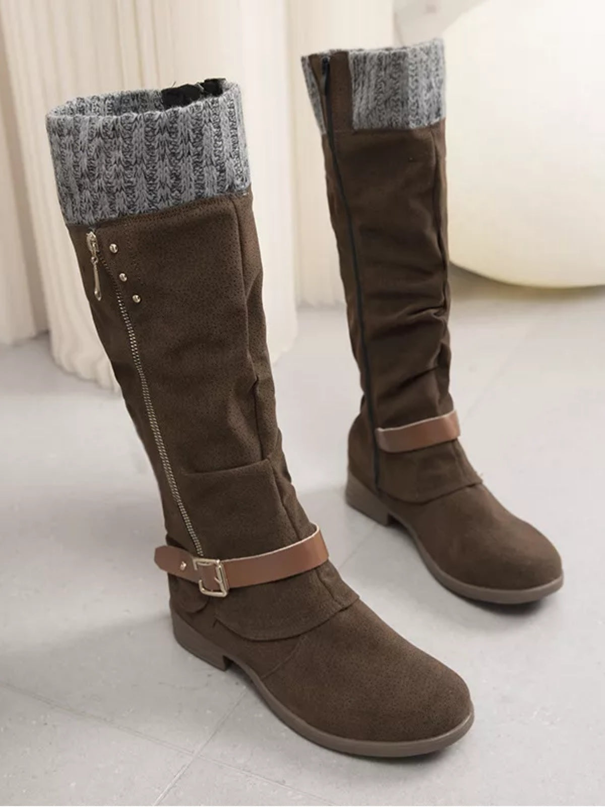 Brown suede knee-high slouch boots feature gray knit cuffs, low heels, side zippers, and buckled ankle straps for a relaxed layered silhouette.