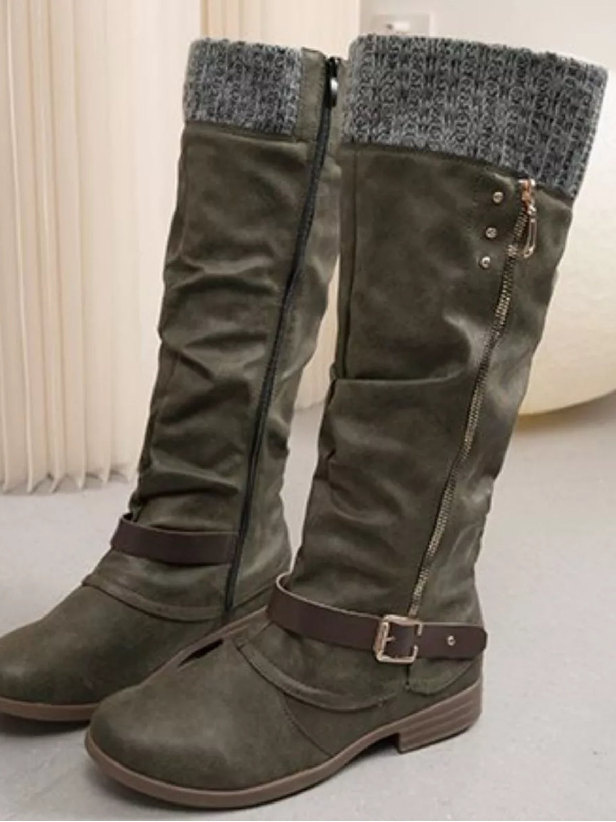 Olive-green suede knee-high slouch boots feature gray knit cuffs, side zippers, ankle buckles, rounded toes, and low rubber heels.