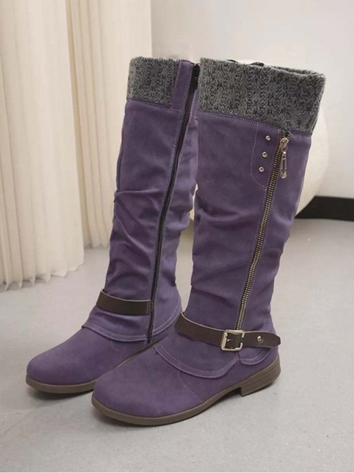 Purple suede knee-high slouch boots feature gray knit cuffs, low heels, rubber soles, side zippers, and buckled ankle straps.