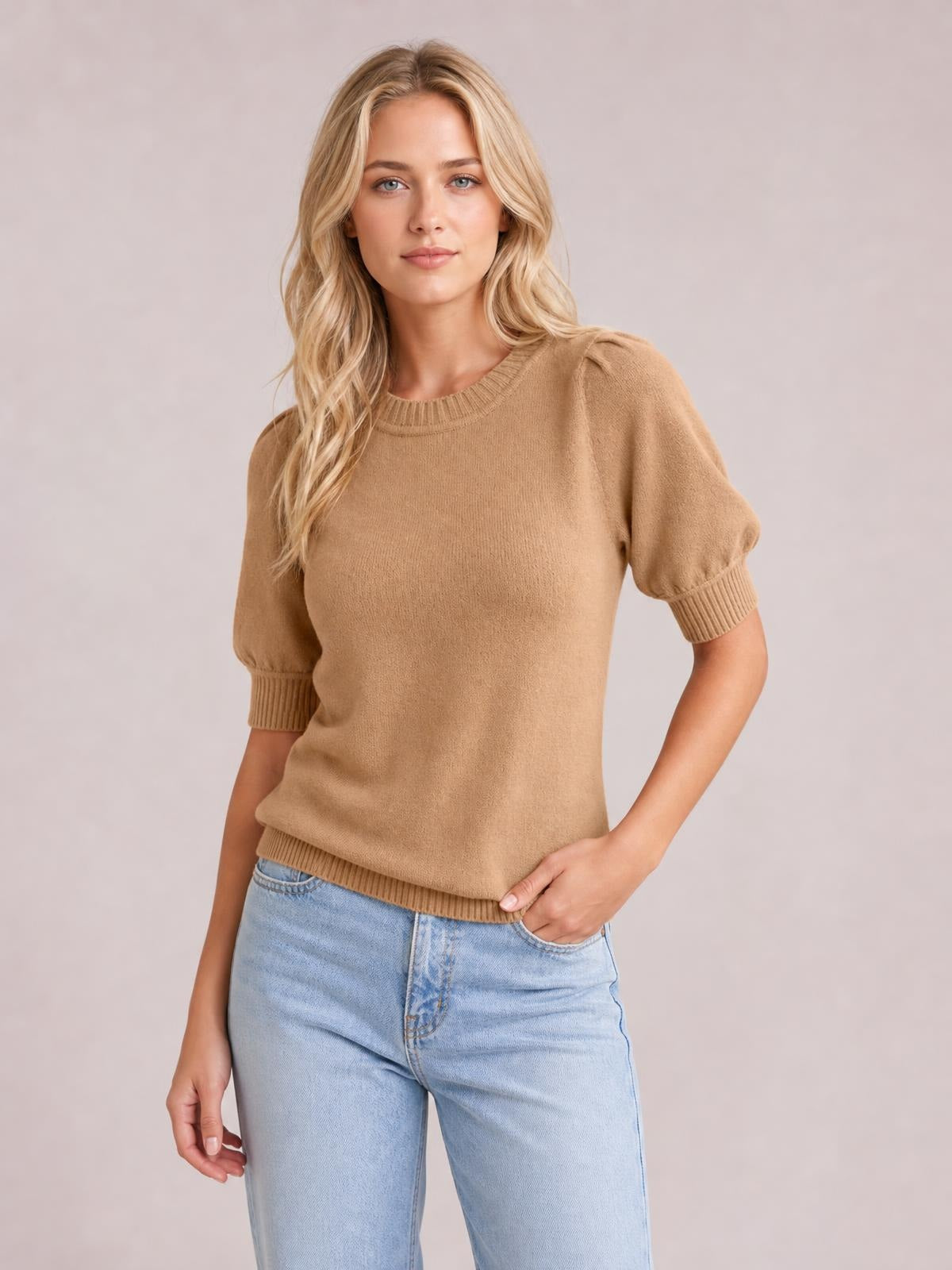 Model wearing a camel knit sweater with short puff sleeves, ribbed crew neckline, sleeve cuffs and hem, paired with light-wash jeans.