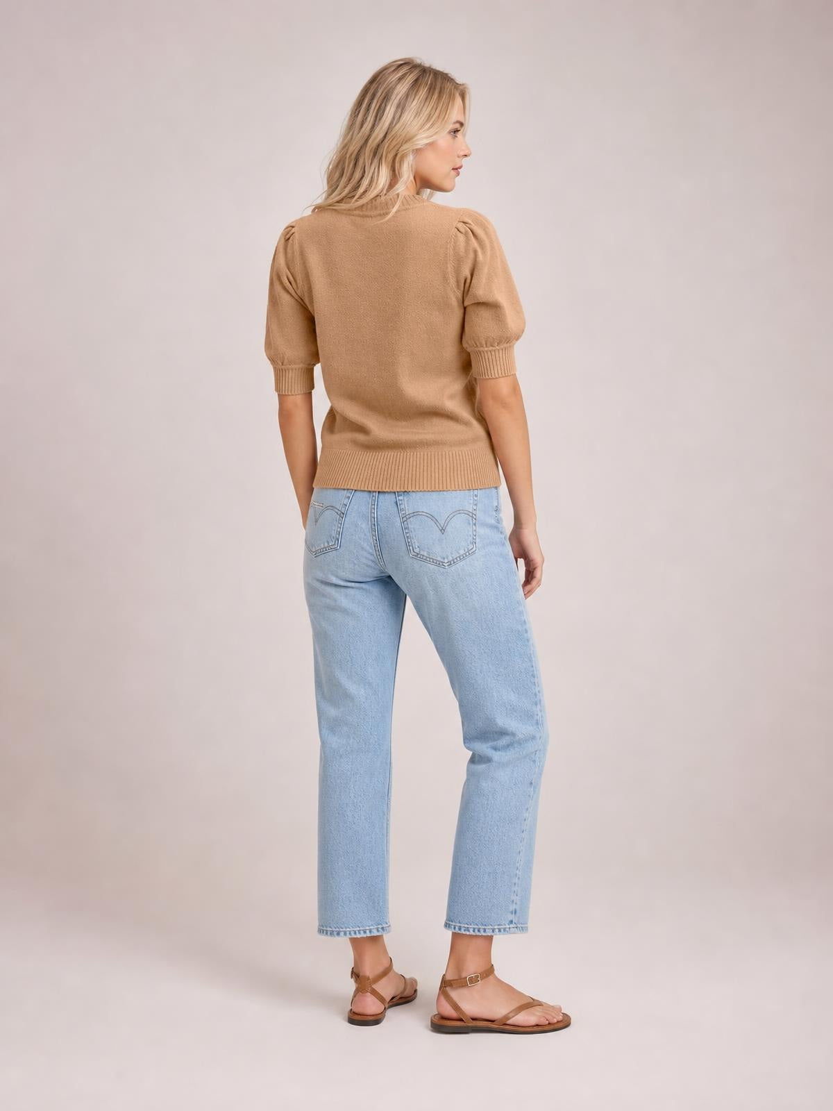 A model wears a camel knit sweater with short puff sleeves, ribbed cuffs and hem, and a fitted silhouette, shown from the back.