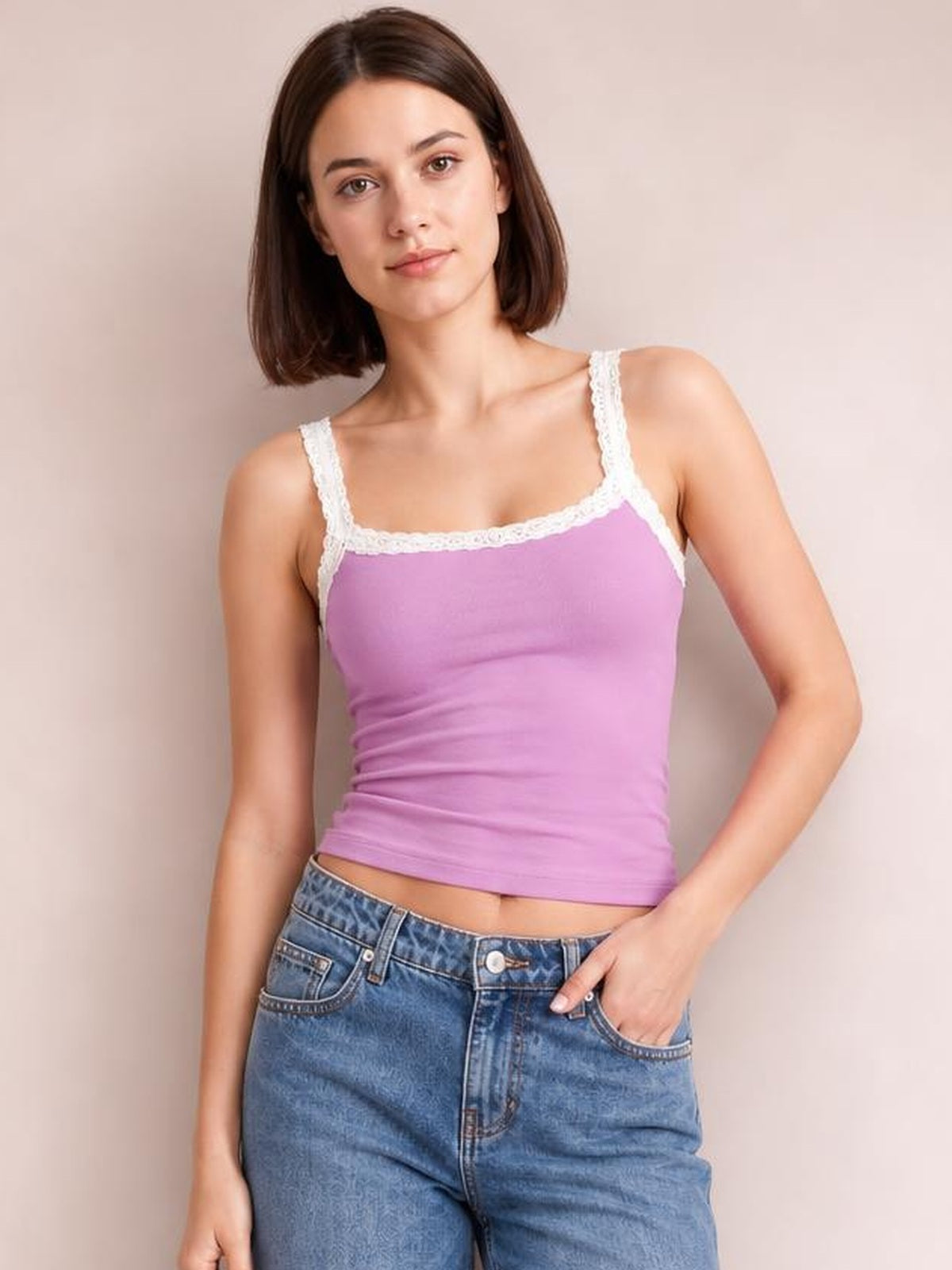 Model poses in a fitted purple cropped cami with delicate white lace trim, square neckline, and slim straps, styled with jeans.