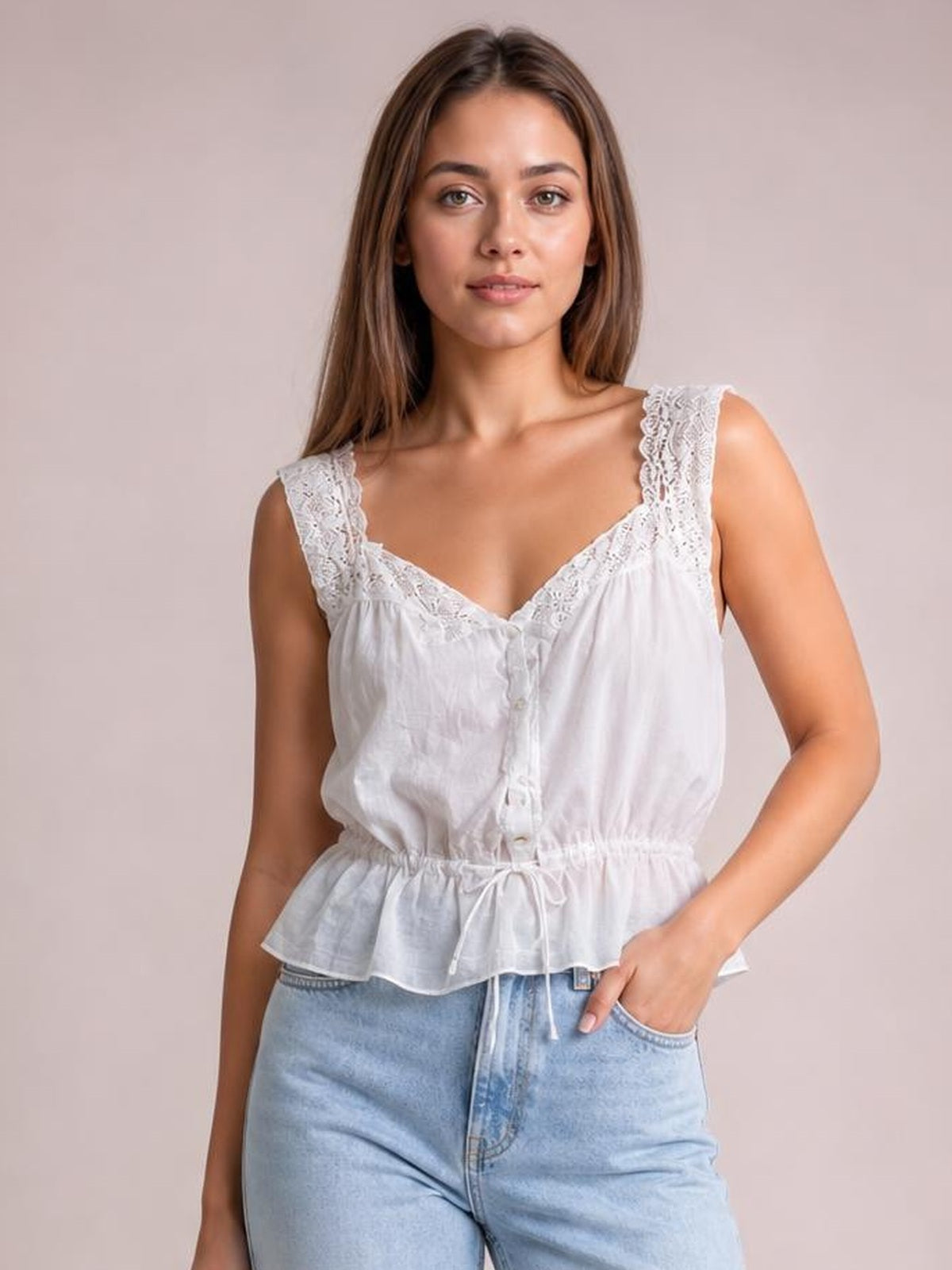 A model poses in a white lace detail tank with wide lace-trimmed straps, buttoned front, adjustable drawstring waist, and flared peplum silhouette.