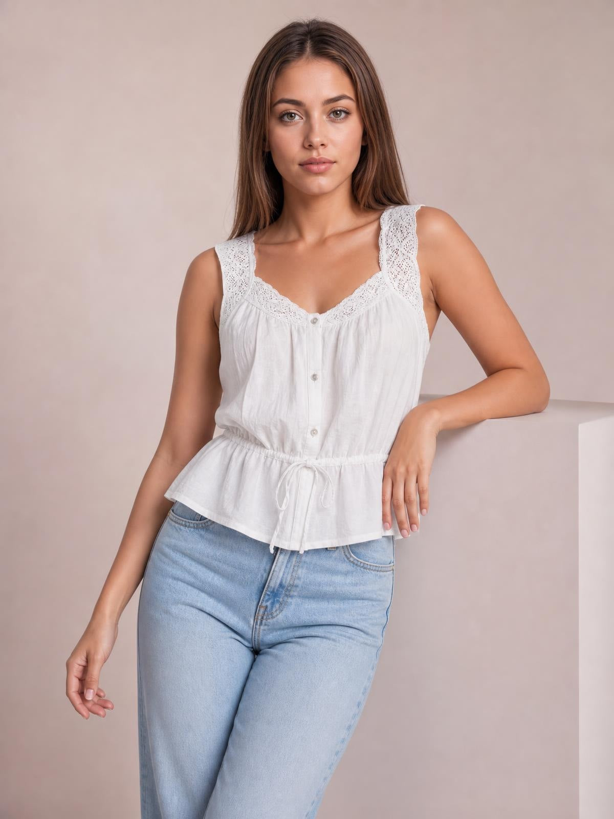 Model wearing a white lace-detail tank with buttoned front, wide lace straps, gathered peplum silhouette, and adjustable drawstring waist, posing with one arm resting.