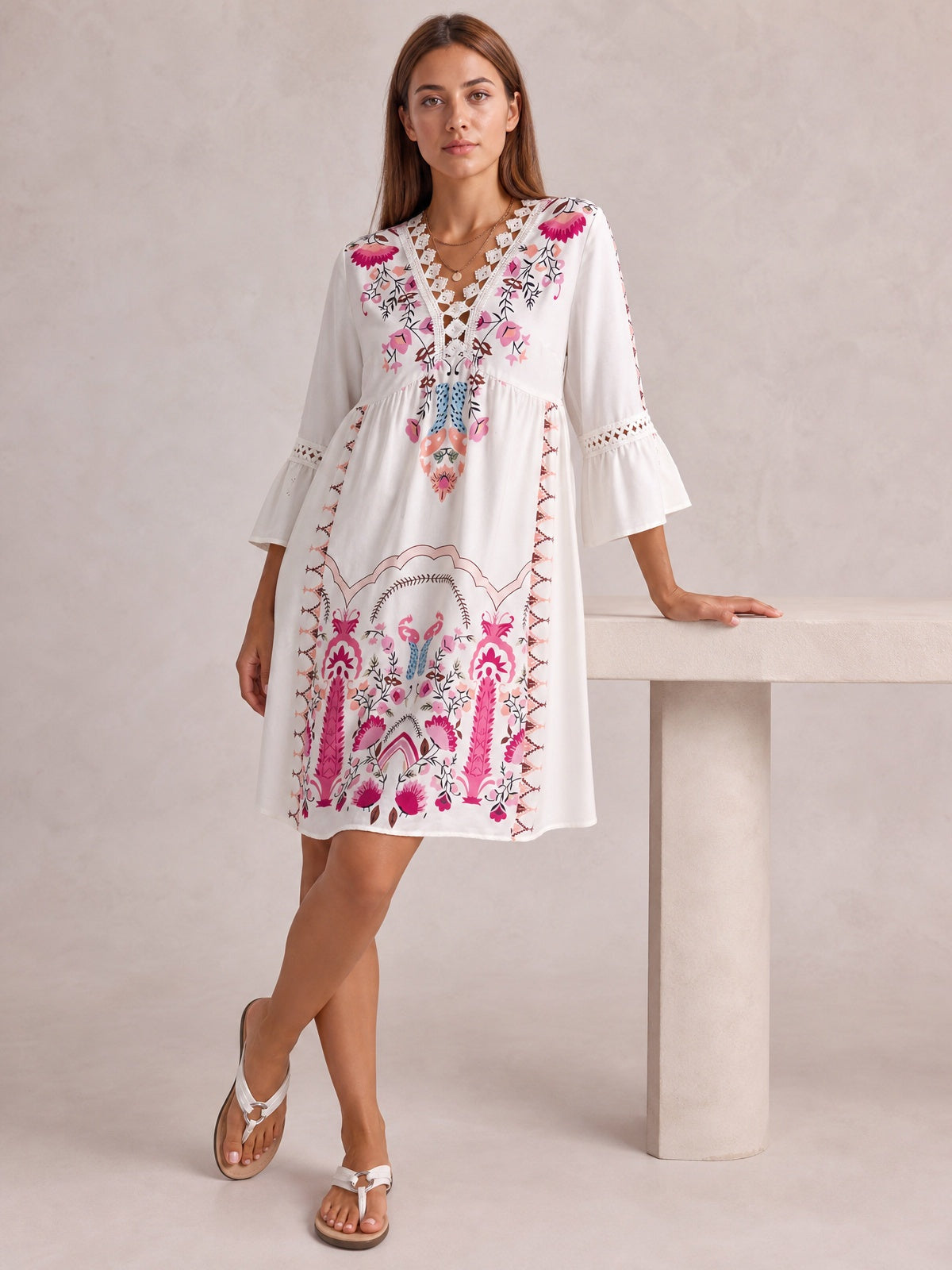 Model in a white printed dress with lace-trimmed neckline, three-quarter bell sleeves, gathered waist, and softly flared short silhouette.