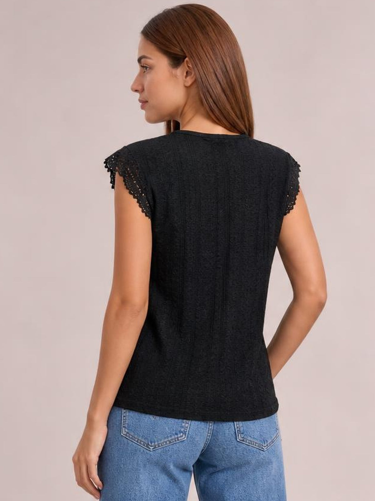 Model shown from the back in a black round-neck top with lace-trimmed cap sleeves, subtle eyelet texture, and a gently fitted silhouette.