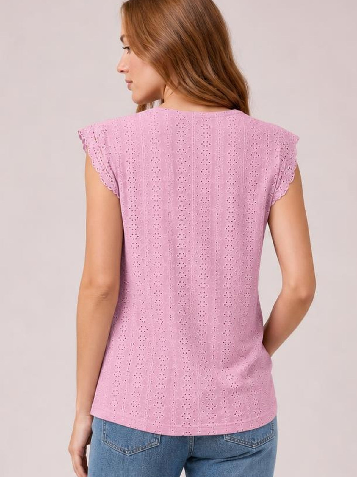 Back view of a woman wearing a pink round-neck top with eyelet detailing, scalloped lace cap sleeves, and a relaxed straight silhouette.