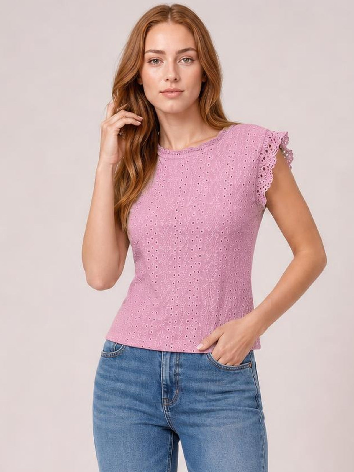 Model wearing a pink eyelet lace-detail top with a round neck, cap sleeves, ruffled edges, and a fitted waist-length silhouette.