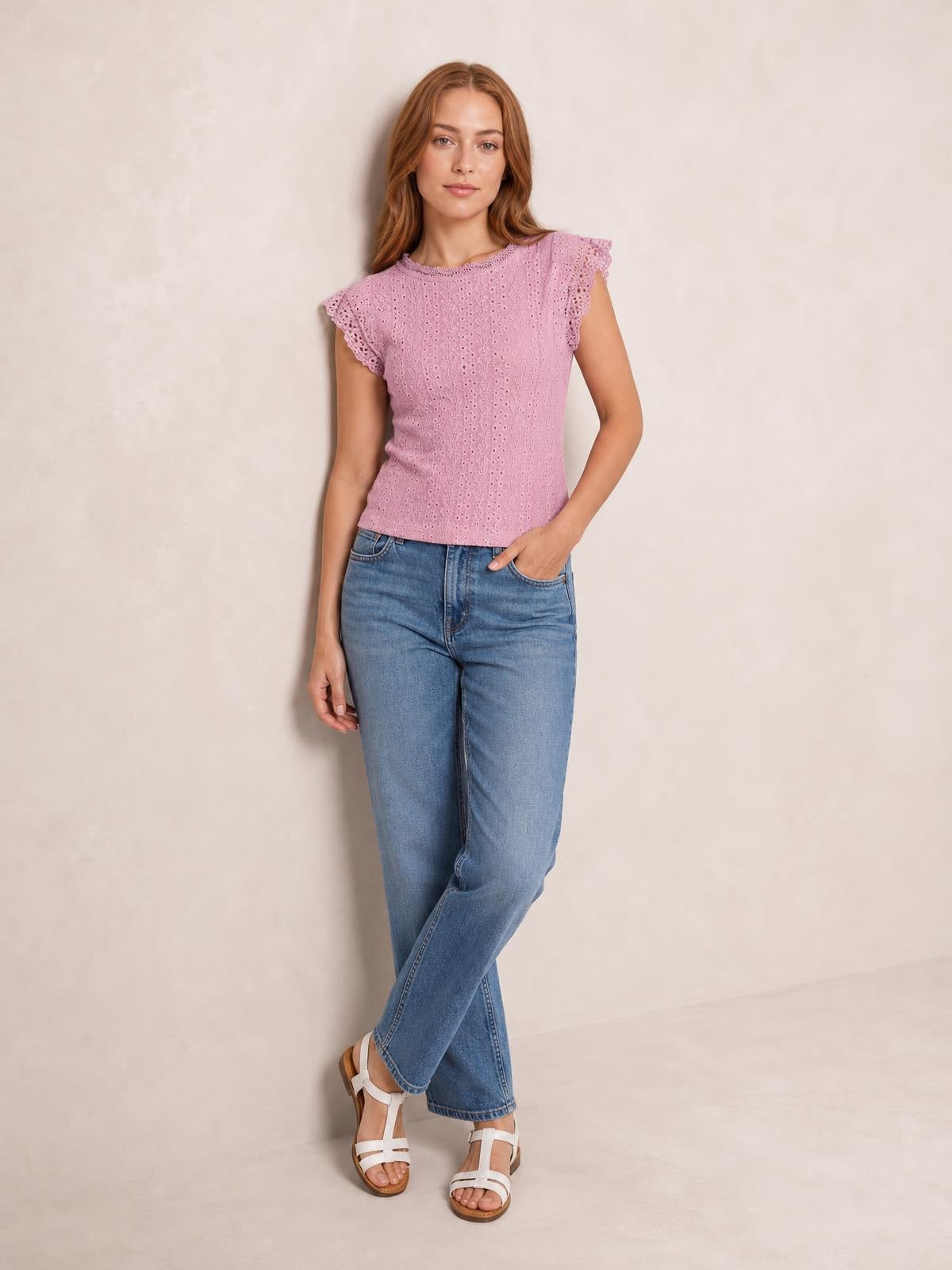 Model wearing a mauve lace detail round neck cap sleeve top with eyelet texture, scalloped sleeves, a fitted silhouette, and a slightly stretchy construction.