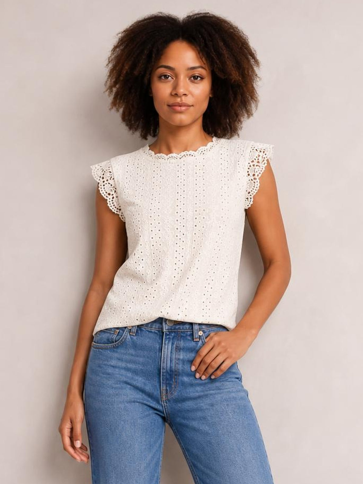 Model wearing a white round neck cap sleeve top with eyelet fabric, scalloped lace-trimmed sleeves and neckline, and a relaxed straight silhouette.