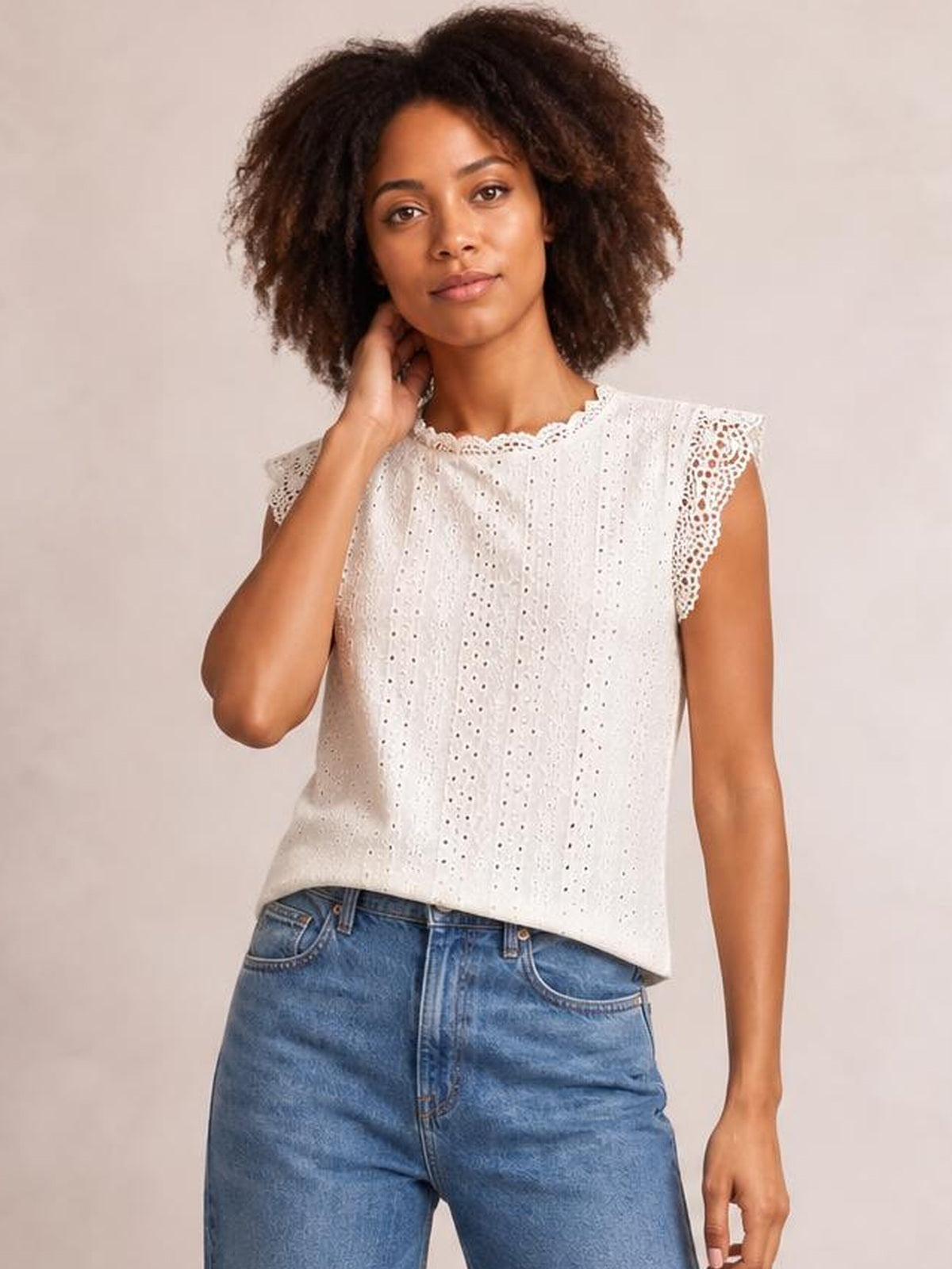 Model wearing a white lace detail round neck cap sleeve top with eyelet fabric, scalloped trim, and a relaxed straight silhouette.