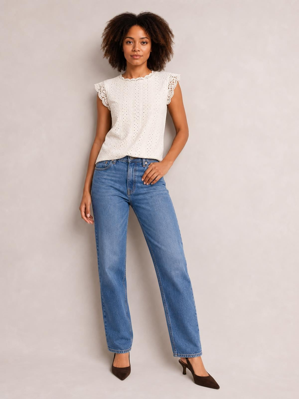 Model poses in a white round-neck cap-sleeve top with eyelet fabric and scalloped lace trim, featuring a relaxed straight silhouette.