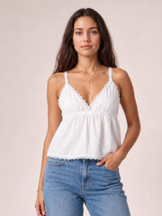 A model wears a white lace detail V-neck cami with thin straps, gathered bust, defined waist seam, and a relaxed flowing silhouette.