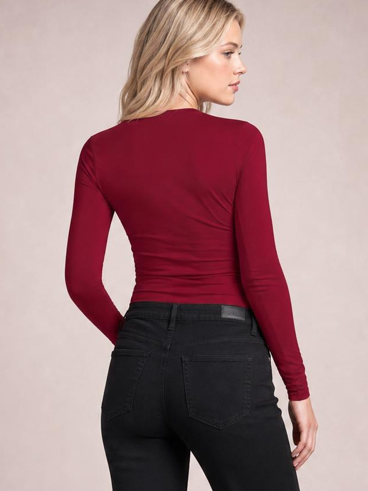 Model turned away to show a burgundy lace detail V-neck long sleeve T-shirt with a fitted, slightly ruched silhouette and stretch construction.
