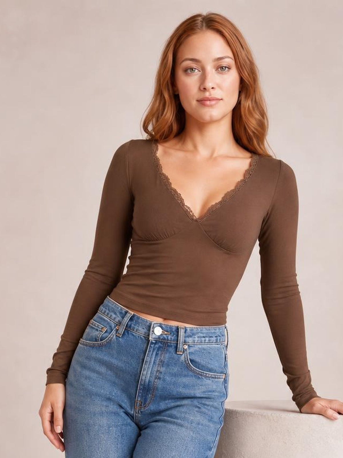 Model wears a brown lace-detail V-neck long sleeve T-shirt with a fitted wrap-style silhouette and slightly stretchy construction.
