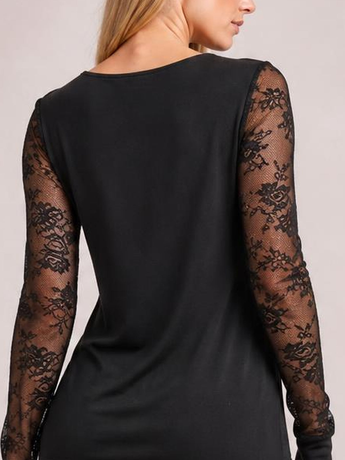 A model shown from behind wears a black long-sleeve top with semi-sheer floral lace sleeves and a relaxed, gently draped silhouette.