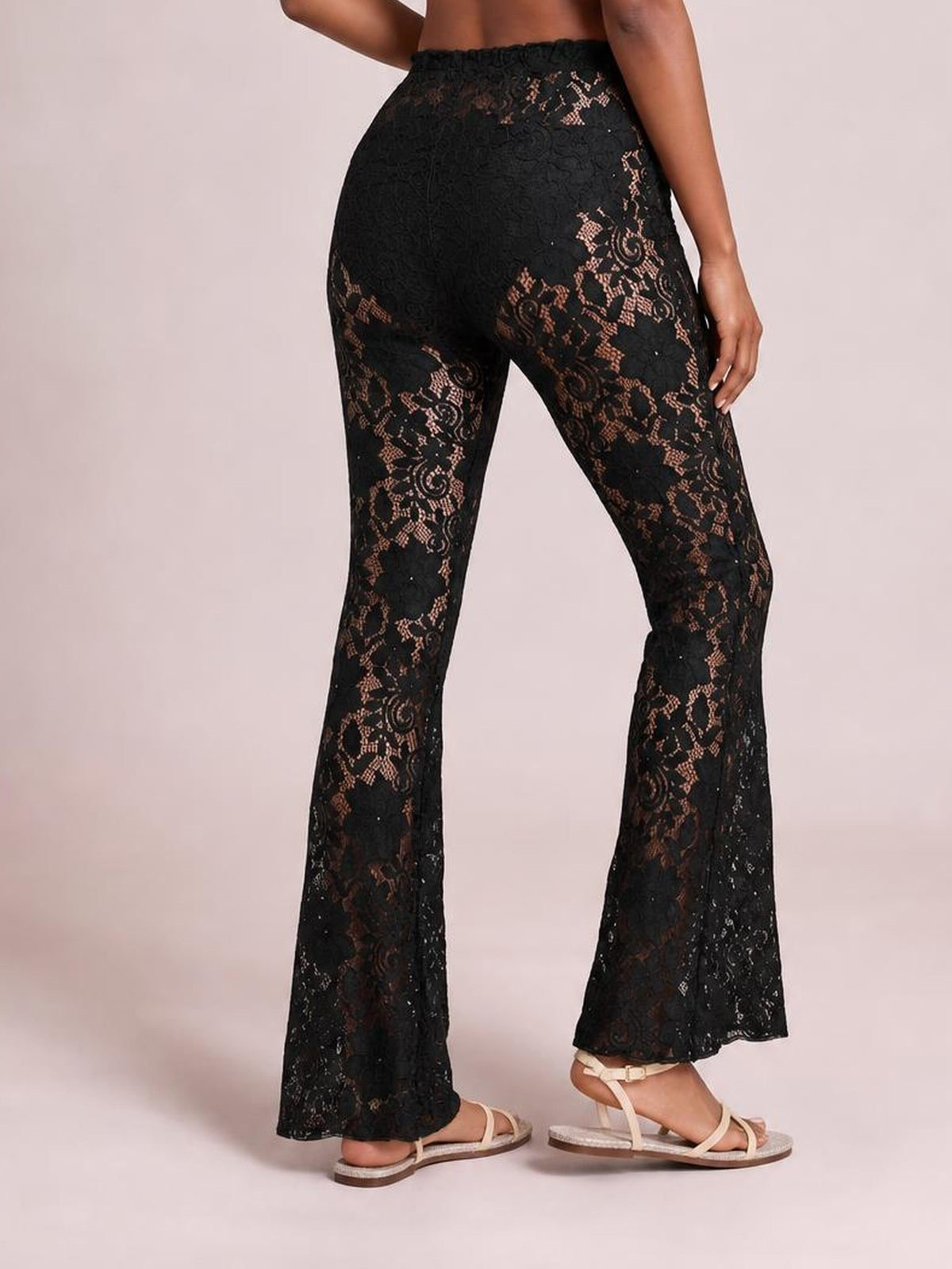 Model poses in black high-waist lace swim pants with a stretchy fit, sheer floral construction, and flared full-length silhouette.