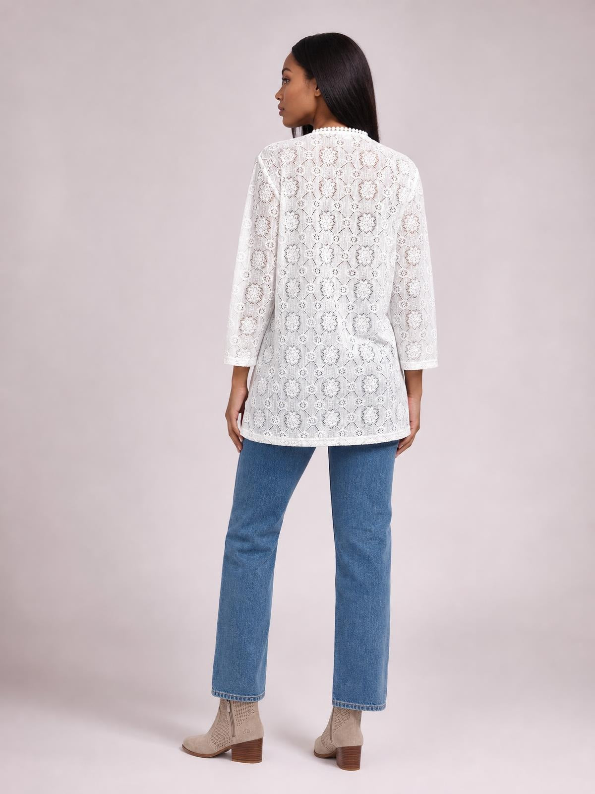 Model stands in a back-facing pose wearing a white lace open front cover up with a long straight silhouette, rounded neckline, and three-quarter sleeves.