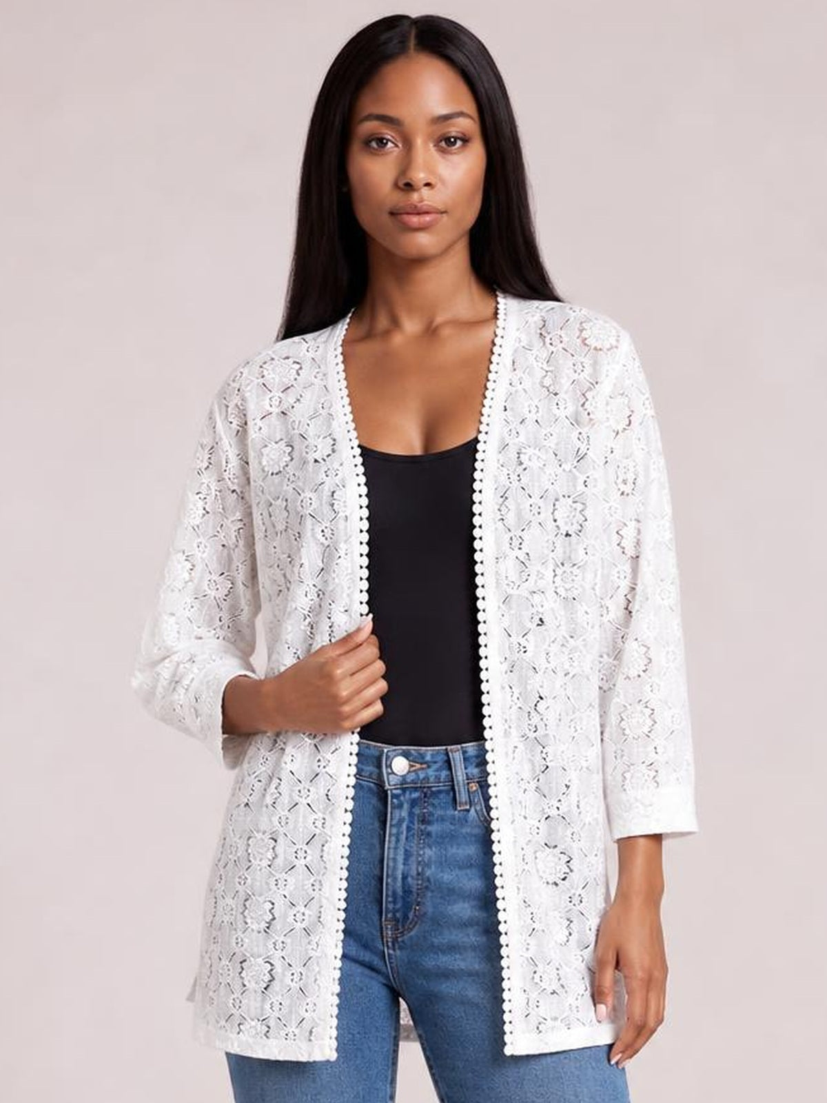 Model holds a white lace open front cover up with three-quarter sleeves, scalloped trim, and a relaxed longline silhouette over a black top.
