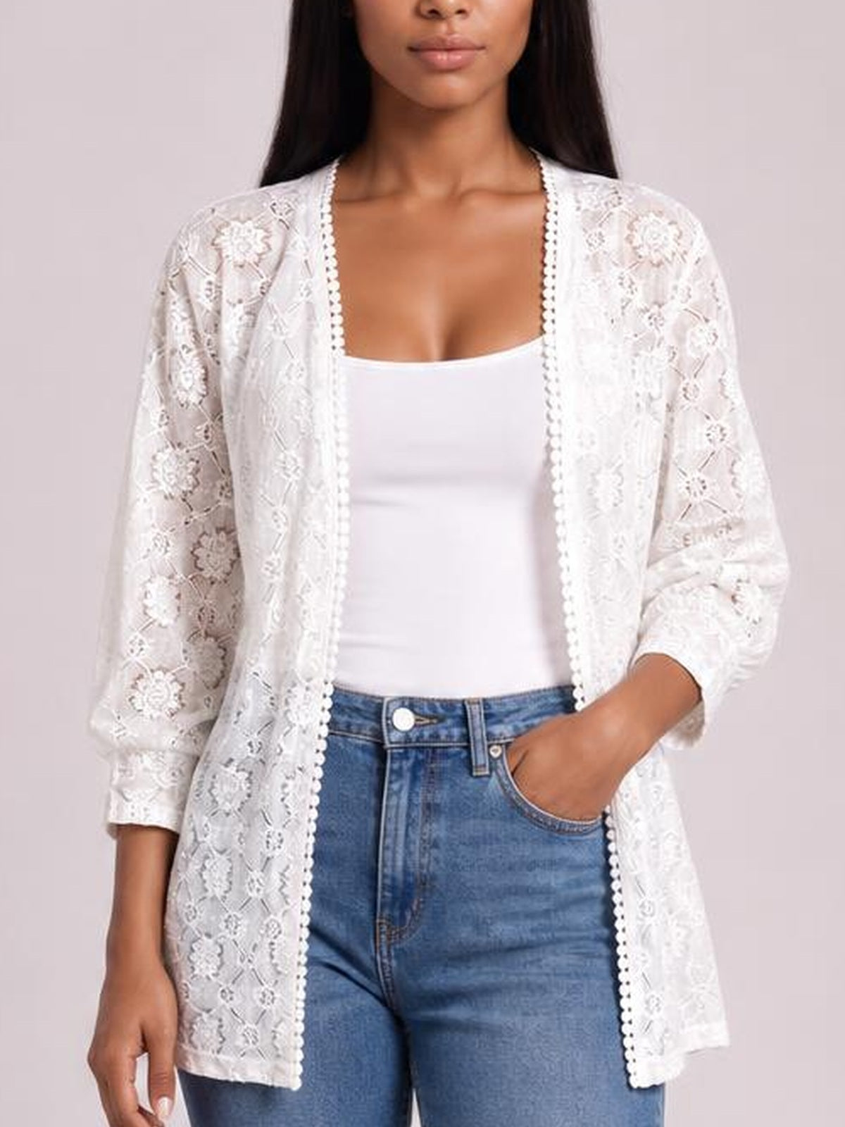 Model wears a white lace open front cover up with floral construction, three-quarter sleeves, and a relaxed longline silhouette over a white top and jeans.