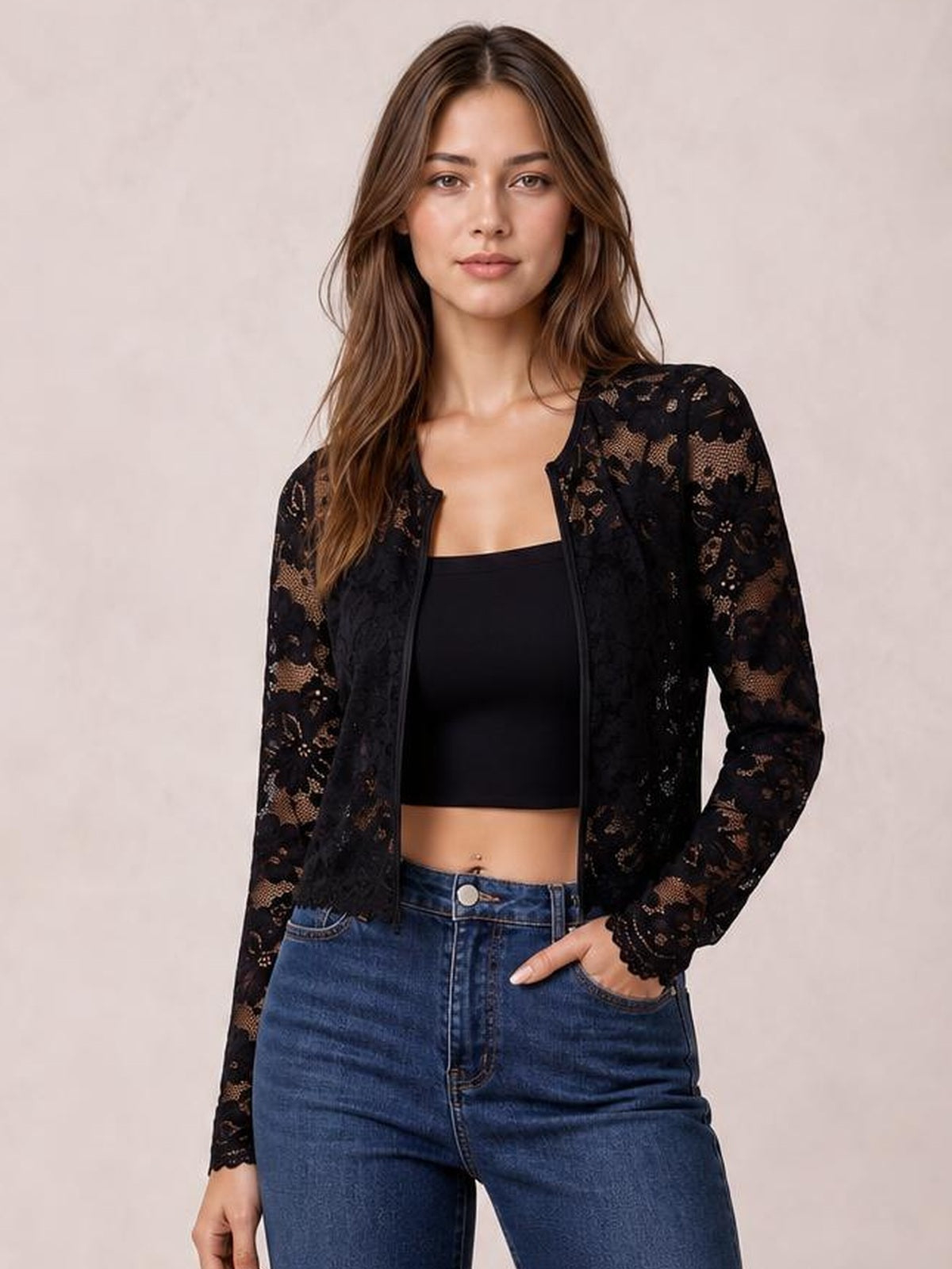 Model wearing a black lace open front long sleeve jacket with a fitted silhouette, scalloped cuffs, and floral construction over a black crop top.